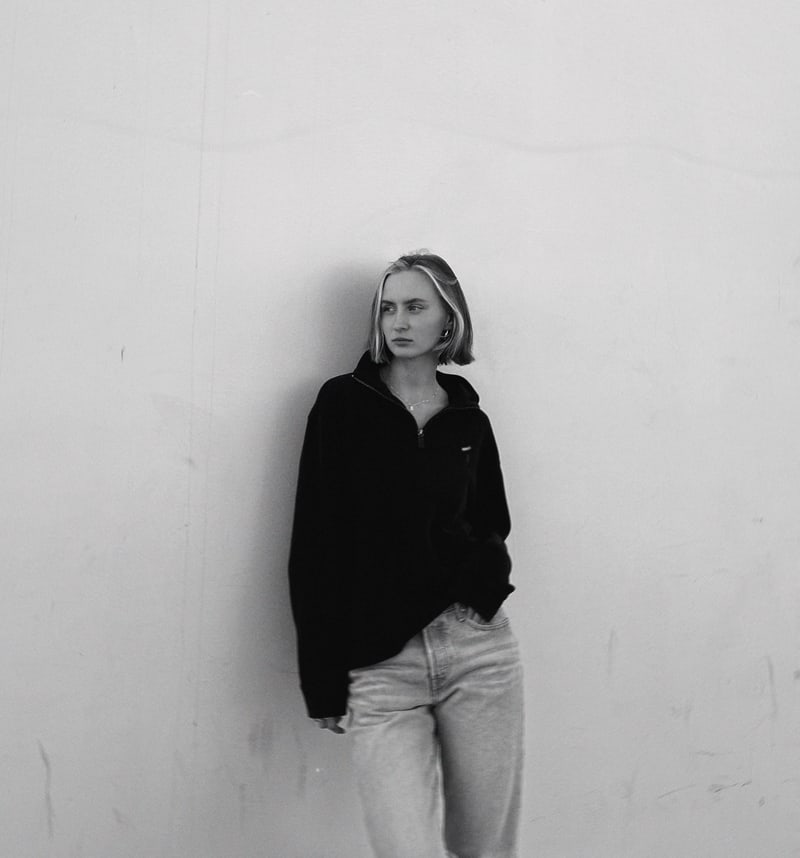 Anna standing against a large pale wall in her Los Angeles studio, photographed in black and white