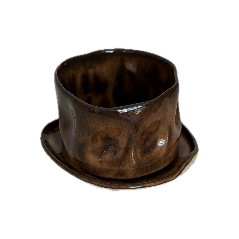 Mottled brown cup and saucer, a handbuilt ceramic cup pressed into dimples under a mottled brown glaze, 10 oz